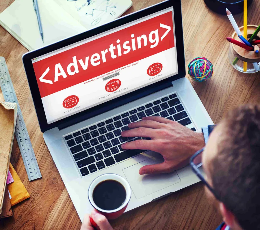 Marketer working on a laptop showing an online advertising dashboard